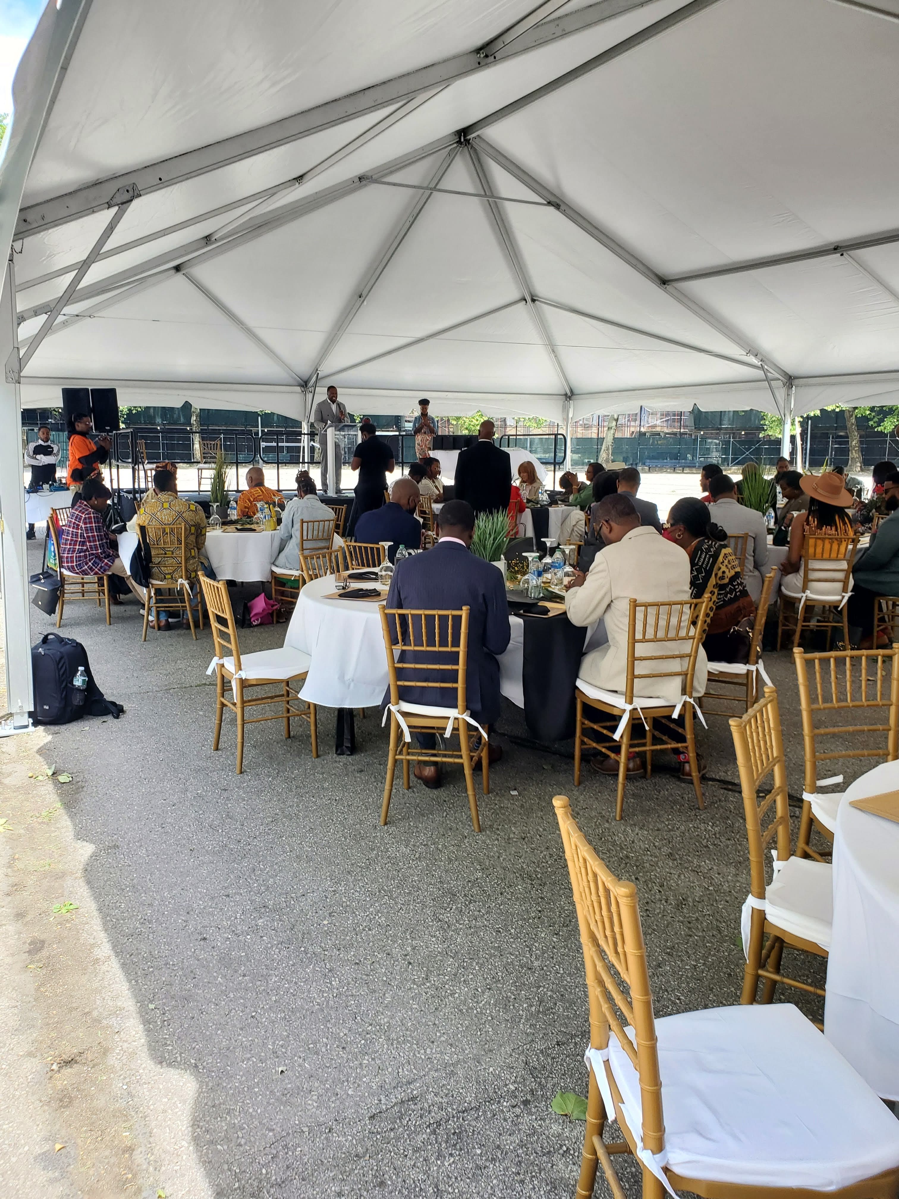 Guests gathered under an outdoor event tent