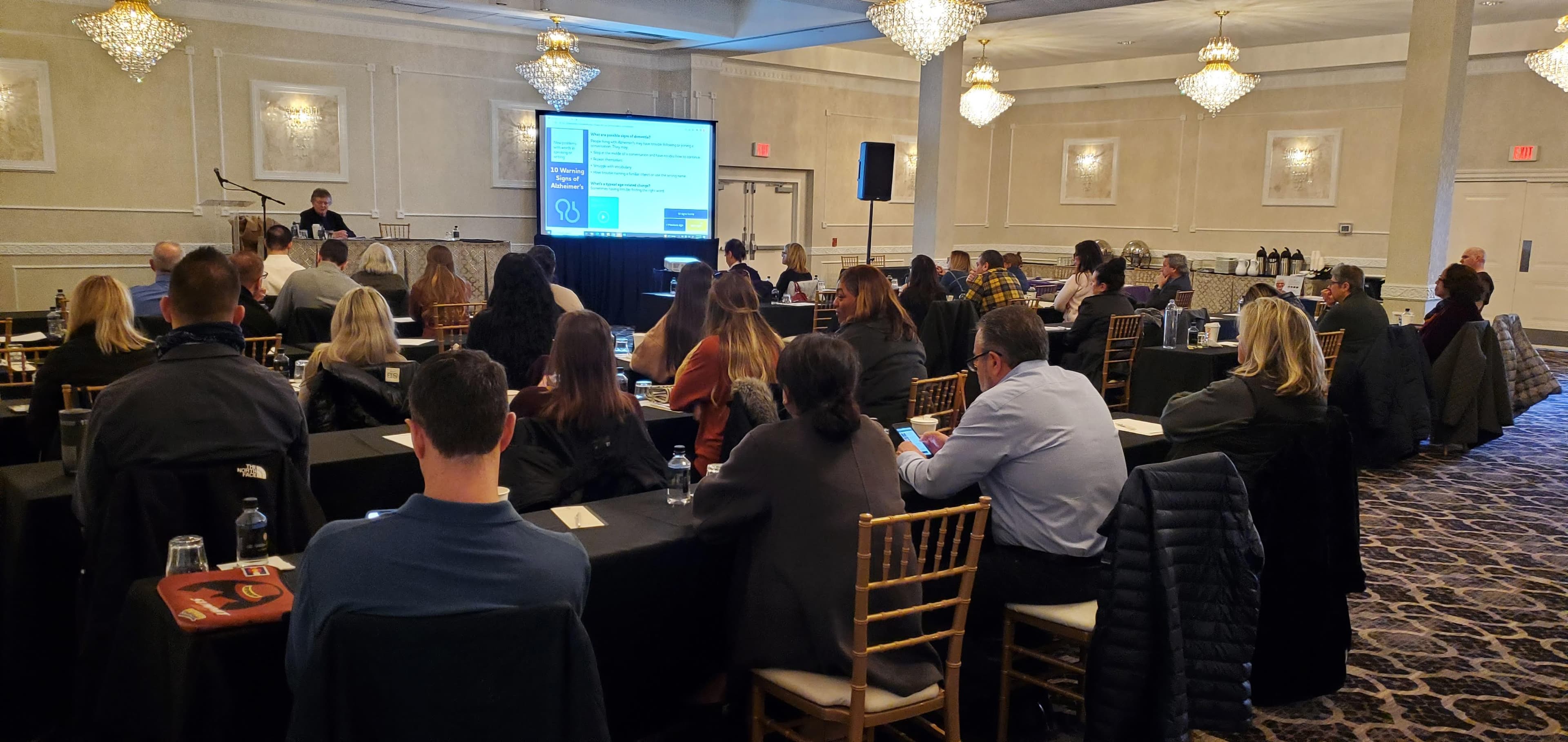 Corporate seminar with projection and seated guests in a chandelier ballroom