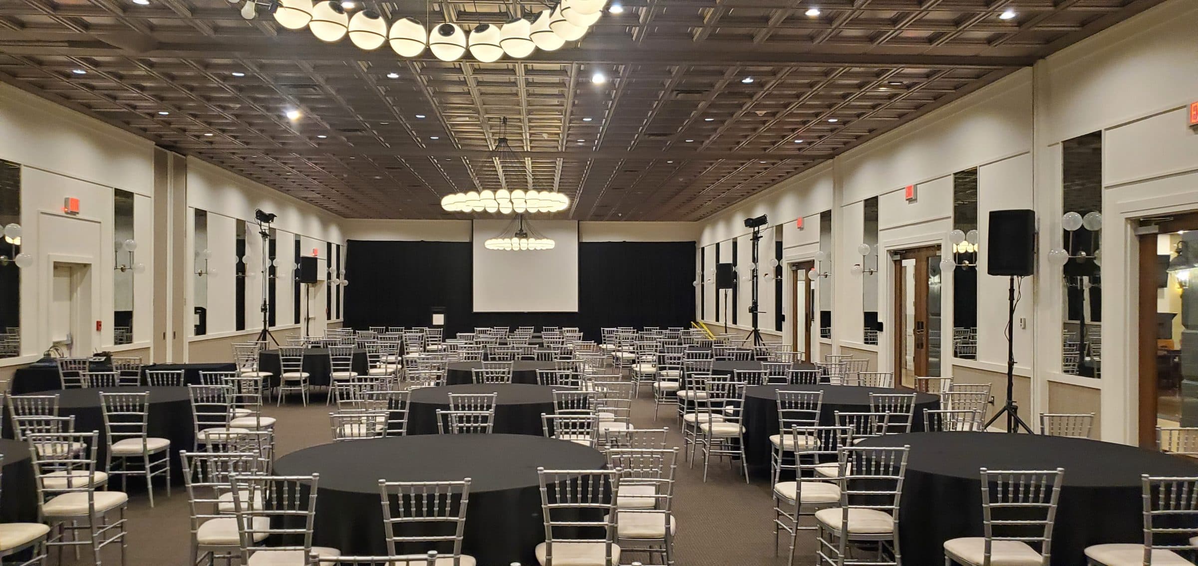 Ballroom set with round tables, a stage, and projection for a corporate program