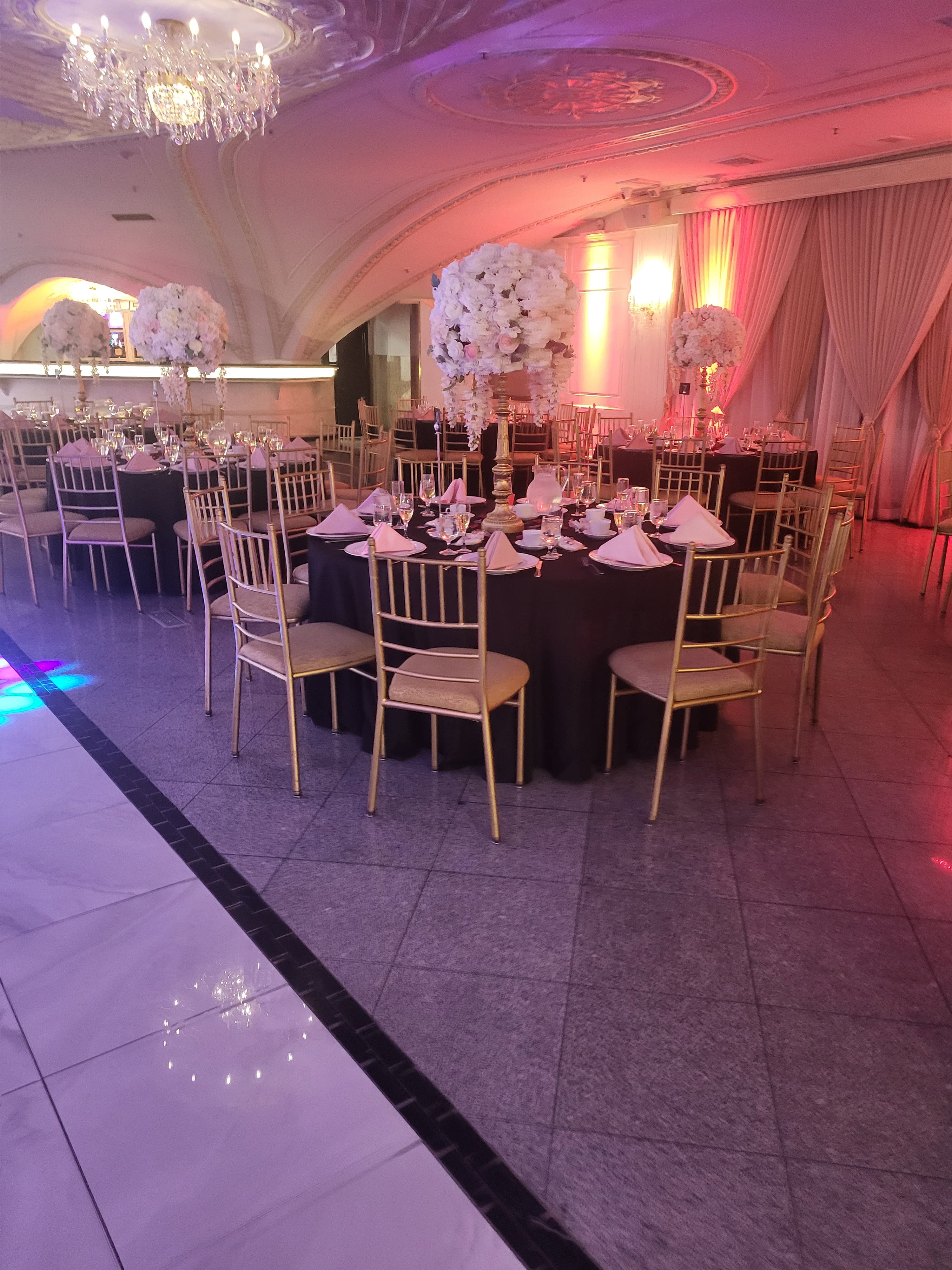 Ballroom gala with black linens, gold Chiavari chairs, and tall floral centerpieces