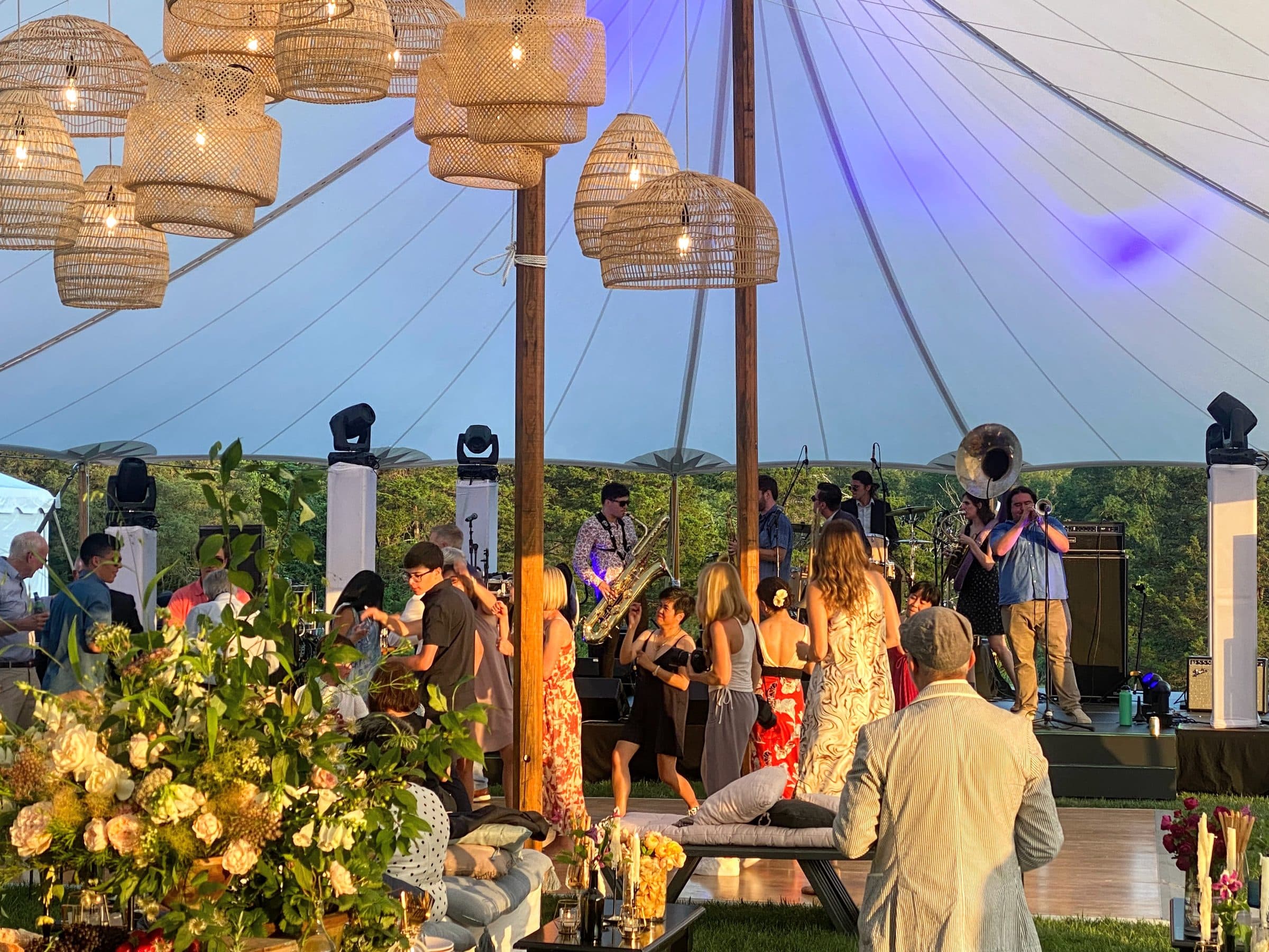 Evening reception under a sail tent with a live band, florals, and lounge seating